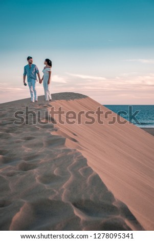 couple walkling sand dunes desert of Maspalomas Gran Canaria, Gran Canary beach Maspalomas sand dunes with men and woman walking desert sand