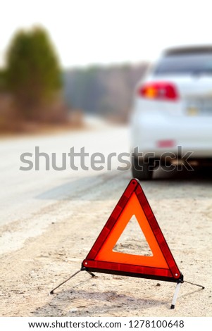White car and a red triangle warning sign on the road