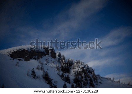 Landscape of snowy Romanian tree-covered mountain with the sky in background