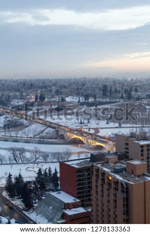 Bird view of the Louise Bridge crossing the Bow River in Calgary Downtown during morning traffic commute in winter under a cloudy sky partial view of  skyscrapers.