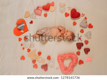 Maternal warmth. Small girl among red hearts. Love. Portrait of happy little child. Sweet little baby. New life and birth. Childhood happiness.Valentines day. Family. Child care.