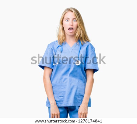 Beautiful young doctor woman wearing medical uniform over isolated background afraid and shocked with surprise expression, fear and excited face.