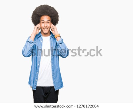 Young african american man with afro hair covering ears with fingers with annoyed expression for the noise of loud music. Deaf concept.