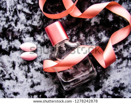 Romantic concept. perfume bottle, flowers, ribbon and jewelry on gray velvet texture background