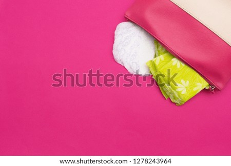 Lady's handbag in which the daily and gynecological pads for menstruation and critical days lie, pink background, copy space, intimate
