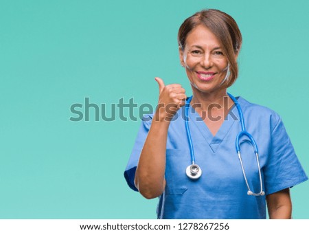 Middle age senior nurse doctor woman over isolated background doing happy thumbs up gesture with hand. Approving expression looking at the camera with showing success.