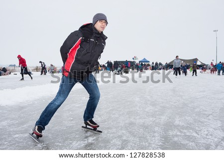 Man skating on the icerink of Eemdijk (Holland) Royalty-Free Stock Photo #127828538
