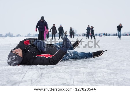 Man fallen on the ice during ice skating (Eemdijk, the Netherlands) Royalty-Free Stock Photo #127828544