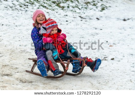 Children enjoy snowshoeing in the snow park where the grass comes out