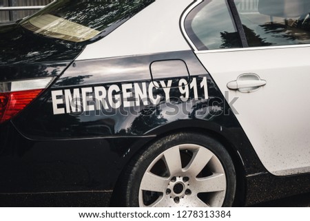 Emergency call 911 sign on a real American police car side. 