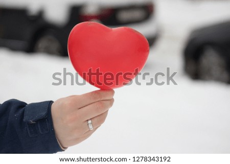 red ball-heart girl holding in her hand on the background of the urban winter landscape. gift, with love on Valentine's day