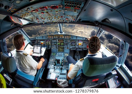 Pilots fly the plane. View from the cockpit of a modern passenger plane on the clouds behind the aircraft window. Royalty-Free Stock Photo #1278379876