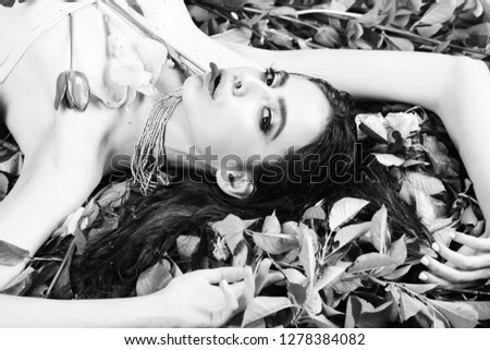 beauty and fashion, spa adn relax, woman with fashionable makeup in green beads with tulip flowers laying on green leaves in spring or summer on natural background