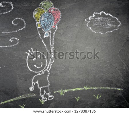 A little boy with balloons painted with chalk on a dark stone surface - A boy flying with balloons over the ground