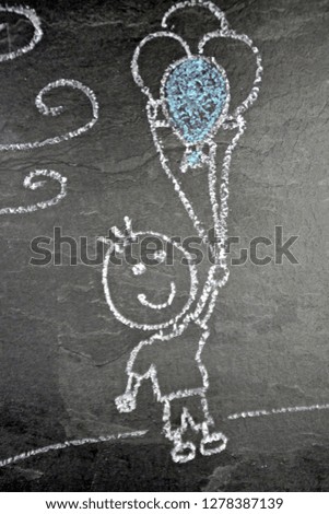 A little boy with balloons painted with chalk on a dark stone surface - A boy flying with balloons over the ground