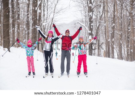 Family with two children cross-country skiing in the winter forest in the snow