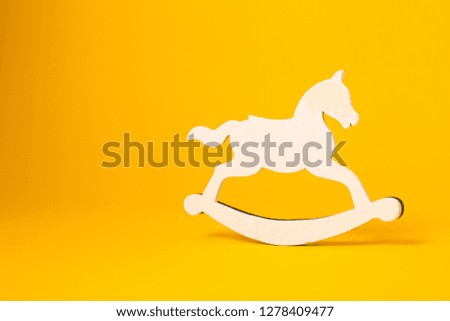 Wooden rocking horse toy on yellow background. Balancing wooden horse silhouette, copy space