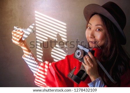 Interesting background for travel. The girl holds the plane and the camera stands near the wall and smiles.