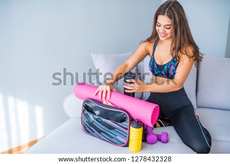 Woman packing bag for the gym. Packing stuff for a gym. Preparing gym bag at home. Woman preparing fitness bag for active day. She always has a bottle of water in her gym bag 
