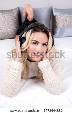 Young woman listening music in bed on headphones