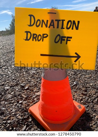 Donation Drop Off sign with arrow affixed to orange safety cone