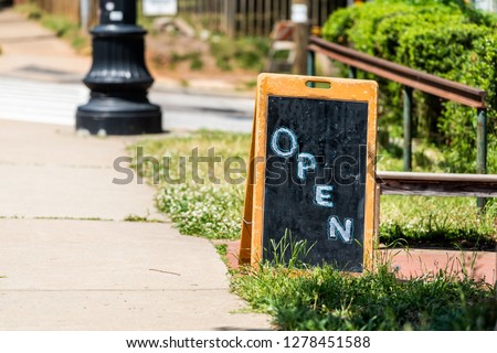 Placard open sign for store shop or restaurant on chalk board chalkboard during day on sidewalk street with nobody