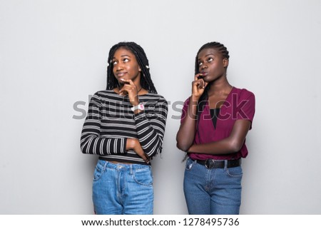 Portrait of two smiling young african women standing together bored isolated over white