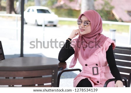 Fashionable hijab women in pink sitting alone on the chair. Confident business women.