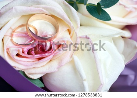 Golden wedding rings on a bouquet of roses, wedding concept