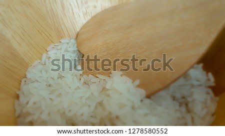 Rice grain on wooden spoon in wooden bowl  background