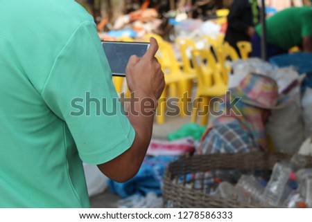 The young man uses a mobile phone to take pictures of garbage collection in low light