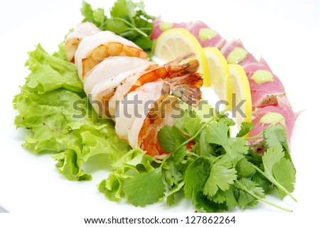 shrimp and tuna with greens and sauce on a white background