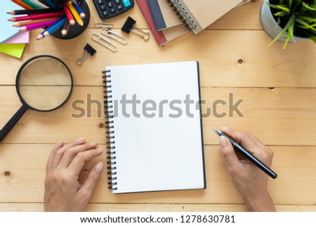 Top view, empty notebook and office supplies on wooden table.