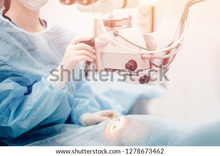 Doctor examines fundus in microscope, patient under sterile cover. Laser vision correction lasik. Royalty-Free Stock Photo #1278673462