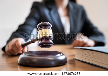 Woman judge hand holding gavel to bang on sounding block in the court room. Royalty-Free Stock Photo #1278676255
