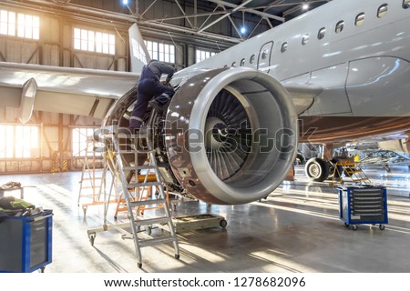 Mechanic specialist repairs the maintenance of engine of a passenger aircraft in a hangar. Royalty-Free Stock Photo #1278682096