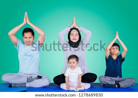 Picture of Muslim family doing yoga exercises while meditating together in the studio
