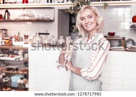 Successful business. Happy delighted woman showing you an OK sign while standing in her bakery
