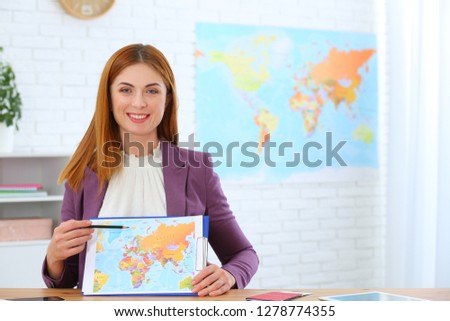 Beautiful consultant showing map in travel agency. Space for text