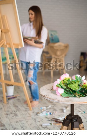 Young female student having classes at art studio, learning how to draw flowers