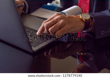 Businessman working on laptop computer with checkbook on the desk, plan to  write and sign cheque at modern office. Paycheck concept.
