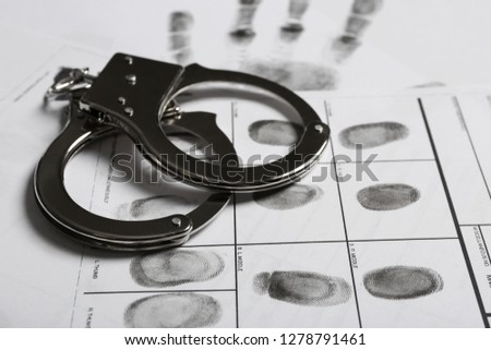 Police handcuffs and criminal fingerprints card, closeup Royalty-Free Stock Photo #1278791461