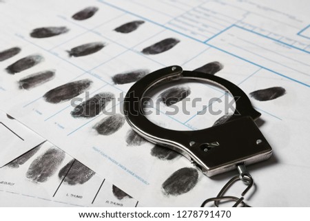 Police handcuff and criminal fingerprints card, closeup Royalty-Free Stock Photo #1278791470