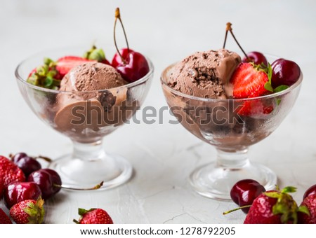 Chocolate ice cream scoops in transparent cups with fresh cherries and strawberries. Tasty fresh dessert