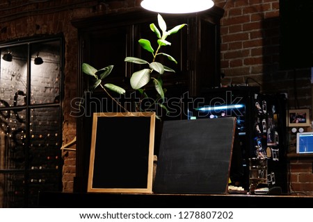 Blank menu board over blur cafe background. Blank blackboard in pub interior. Mock up Restaurant Food Menu Design with Chalkboard Background 