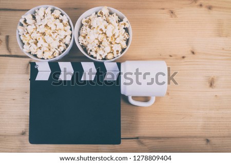 Movie clapper board with coffee cup and popcorn on wooden background