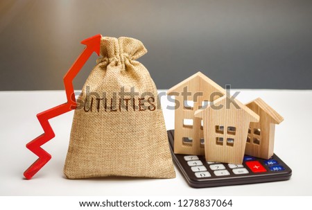 Money bag with the word Utilities and an up arrow and houses on a calculator. The concept of raising prices for the use of utilities. Payment of bills. Rising prices for water, electricity and heating Royalty-Free Stock Photo #1278837064