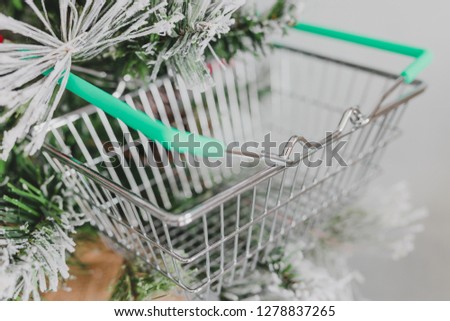small Christmas tree with shopping basket hanging among its branches, concept of holiday shpping for food and presents