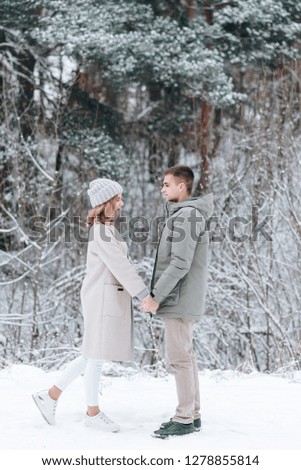 Romantic young couple is hugging in a winter pine forest. Young people, romantic lifestyle and love, outdoors. Young couple portrait. Beautiful pretty girl is hugging  handsome boy.