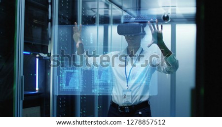 Medium shot of a young female technician in VR glasses using then turning off a virtual interface while working in a data center